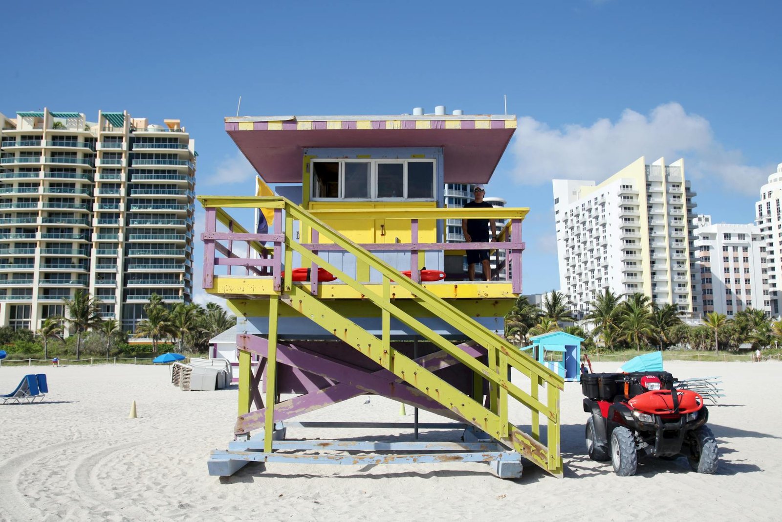 Vibrant lifeguard tower on Miami Beach with buildings in background.