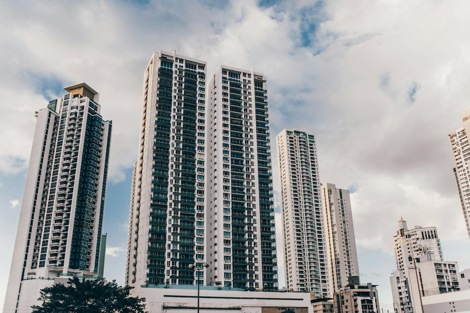 Urban skyline with tall skyscrapers under a partly cloudy sky, showcasing modern architecture.