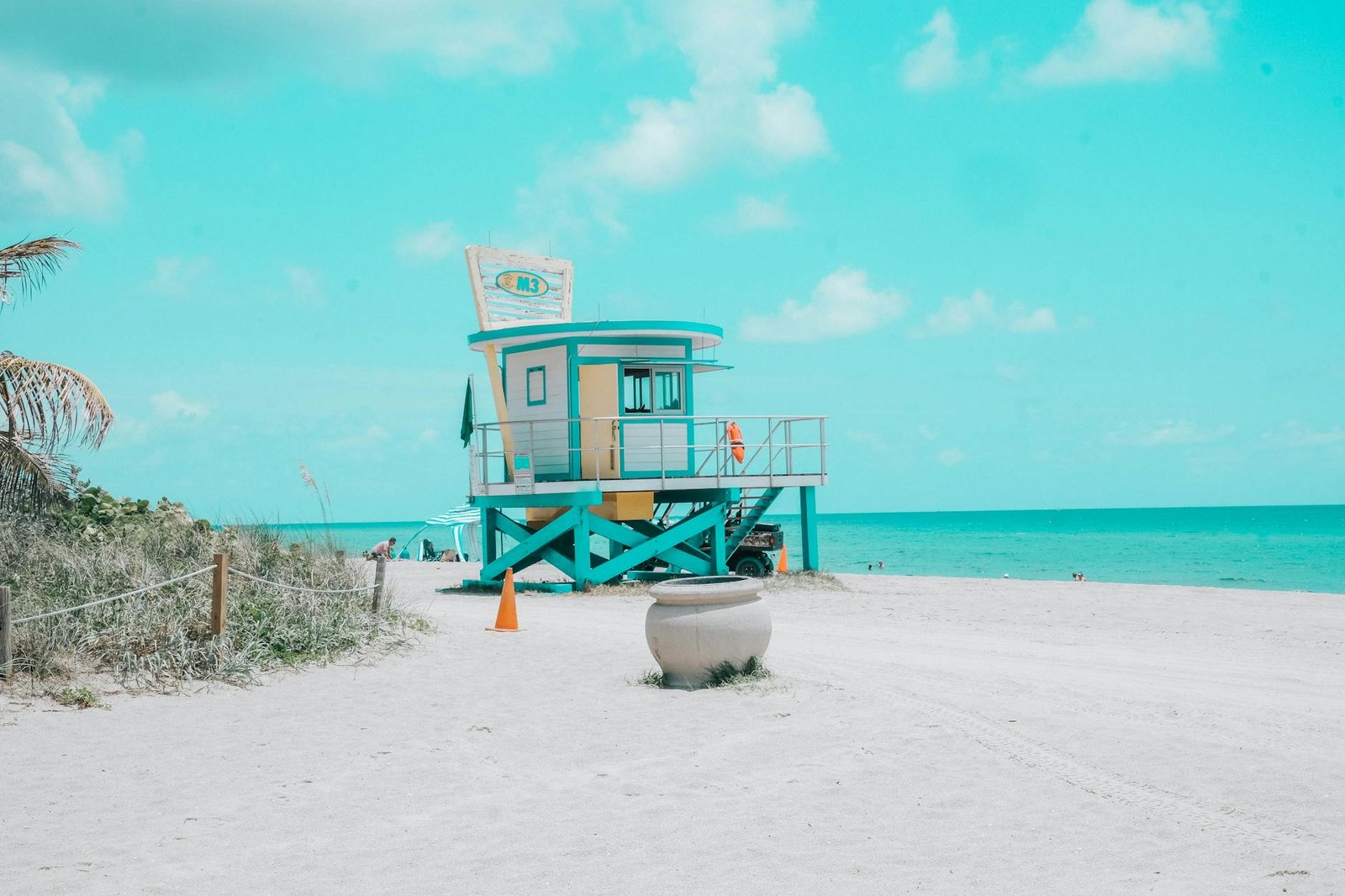 Bright beach day featuring a colorful lifeguard tower and calm ocean waves.