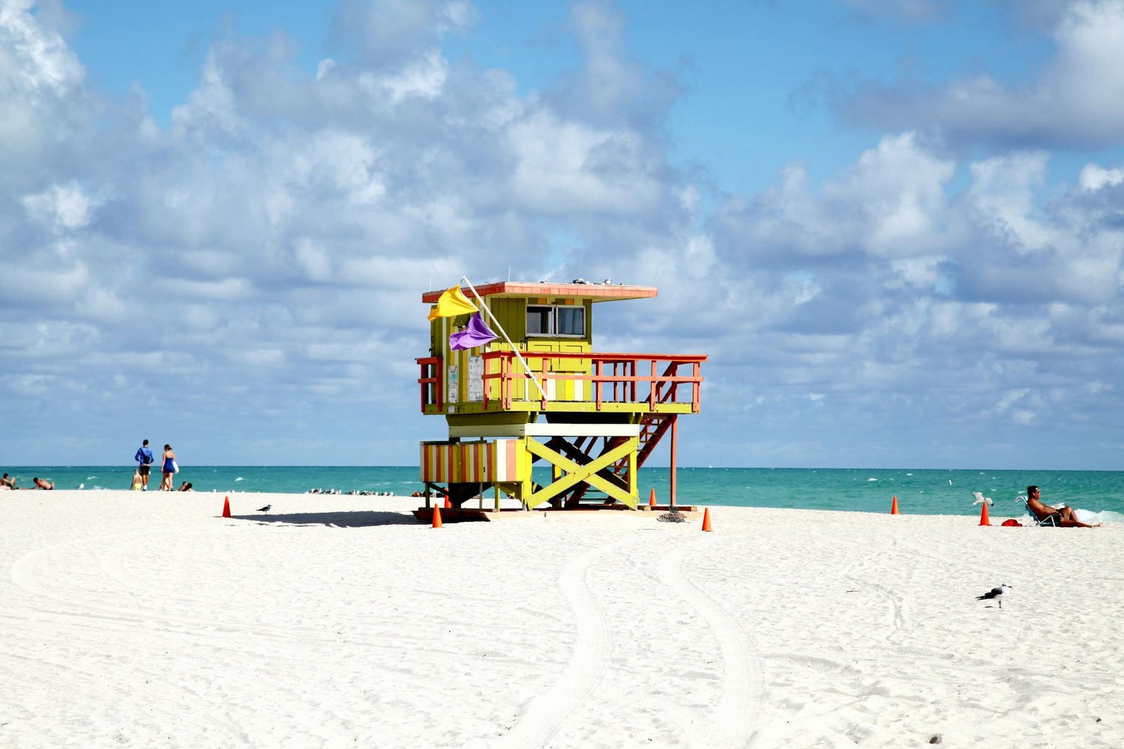 Colorful lifeguard tower on sandy Miami Beach with bright sky and ocean view.