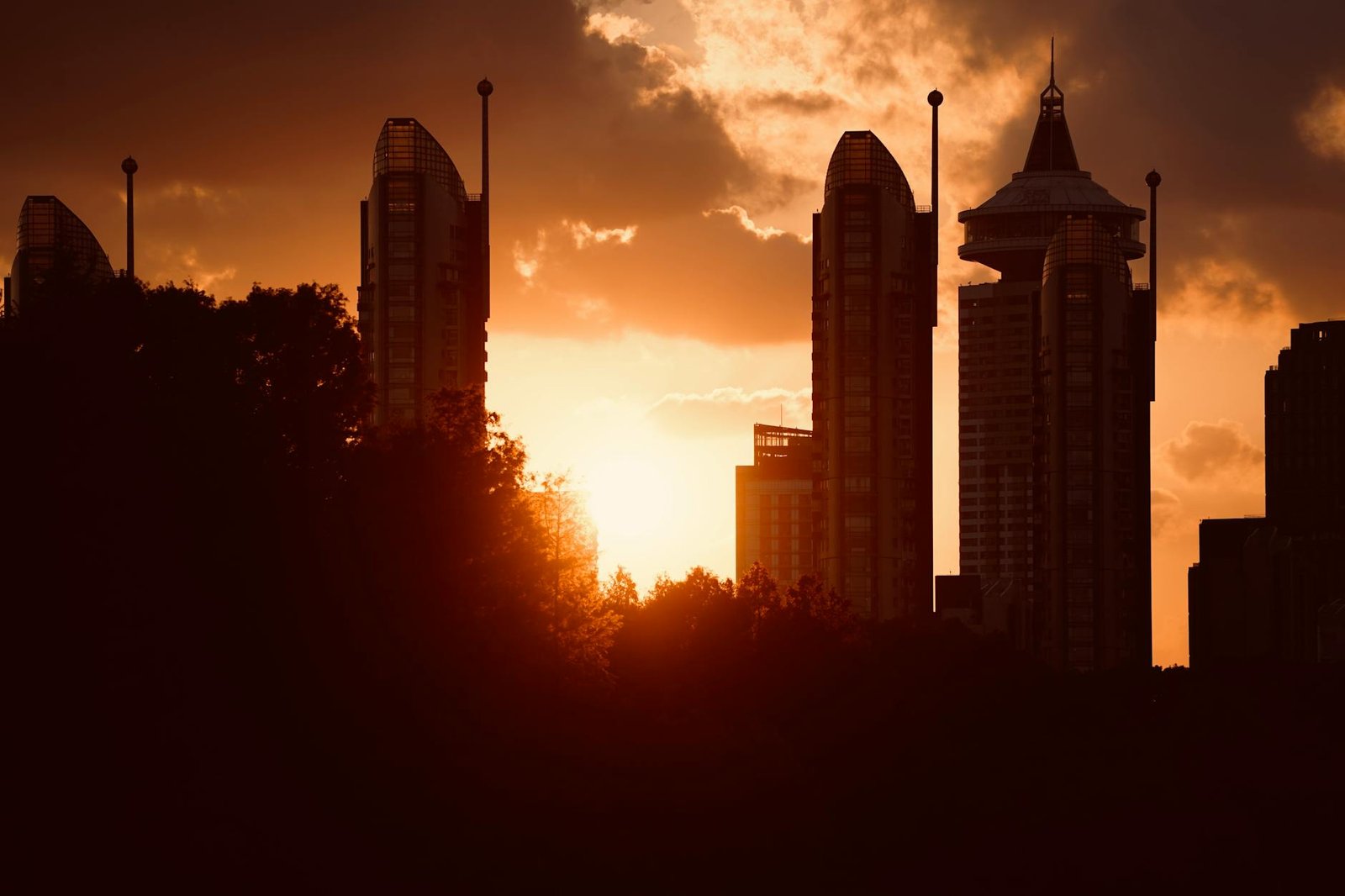 Silhouetted skyscrapers set against a vibrant sunset, depicting modern cityscape.